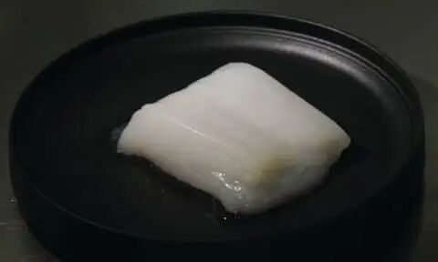 黑色培养皿中有一团白色的东西，看起来像鸡肉