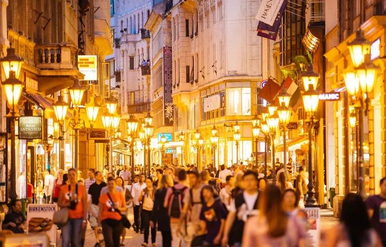 Crowded pedestrian street in Budapest, Hungary, illuminated by street lights.