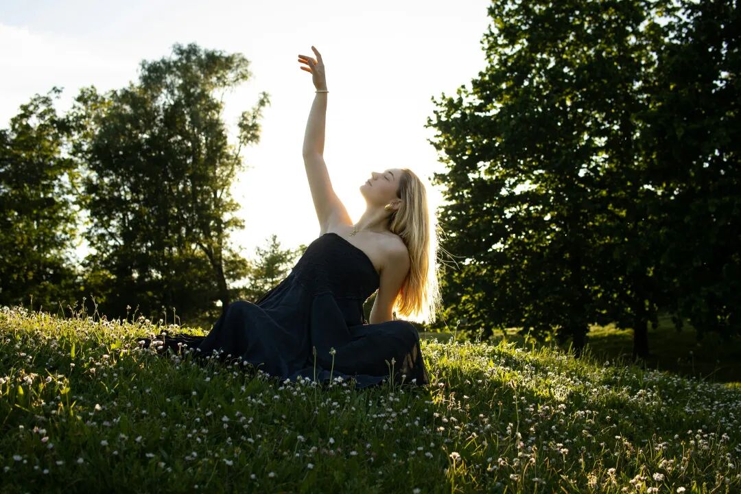 A woman in a black dress sitting in a field