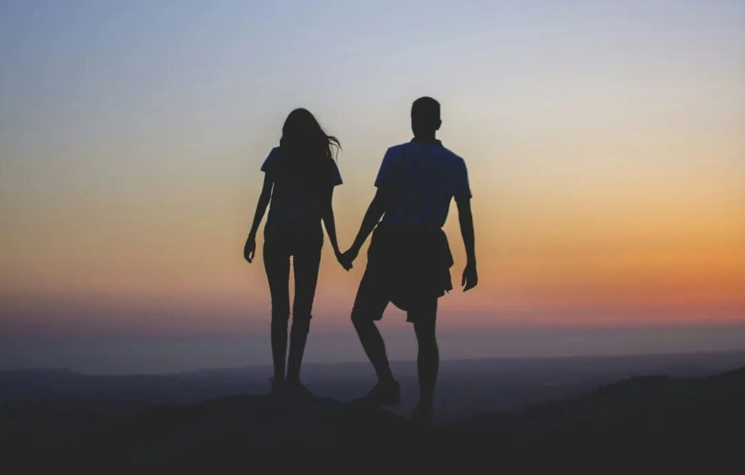 man and woman holding hands in silhouette photography