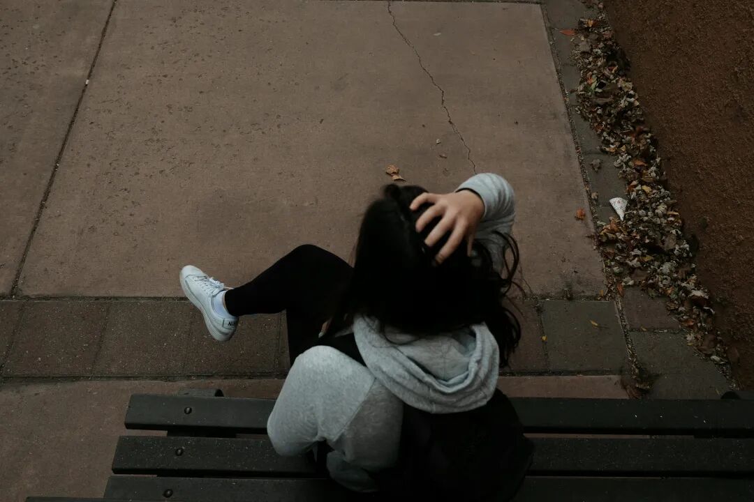 一个人坐在人行道上的长凳上