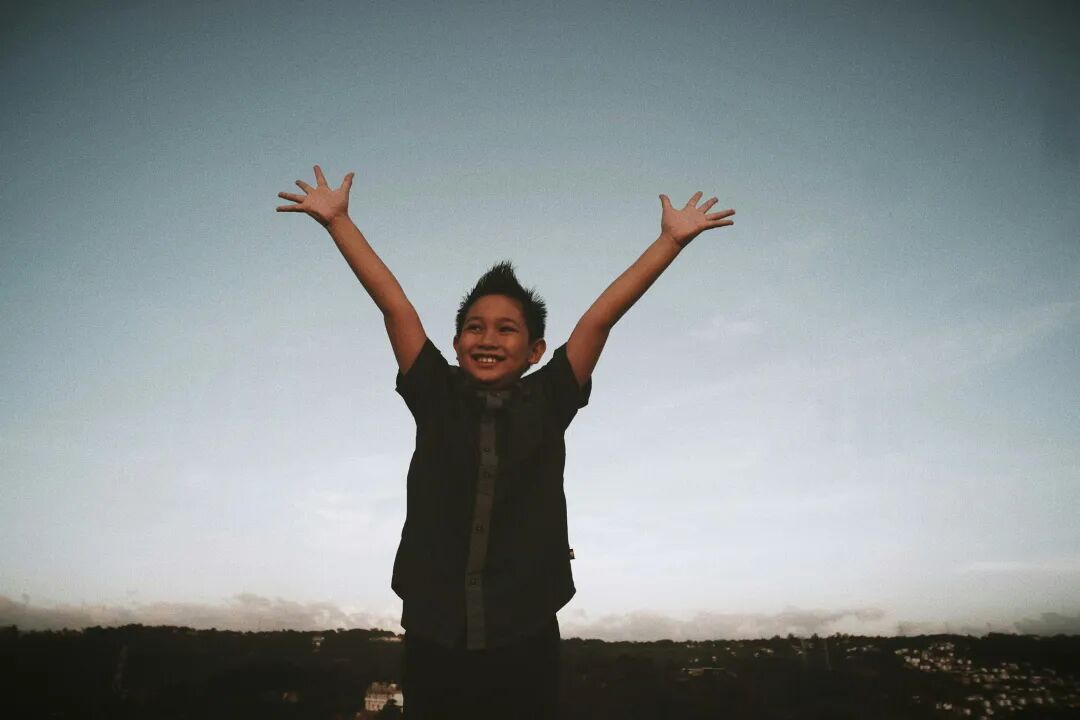 a young boy with his hands up in the air