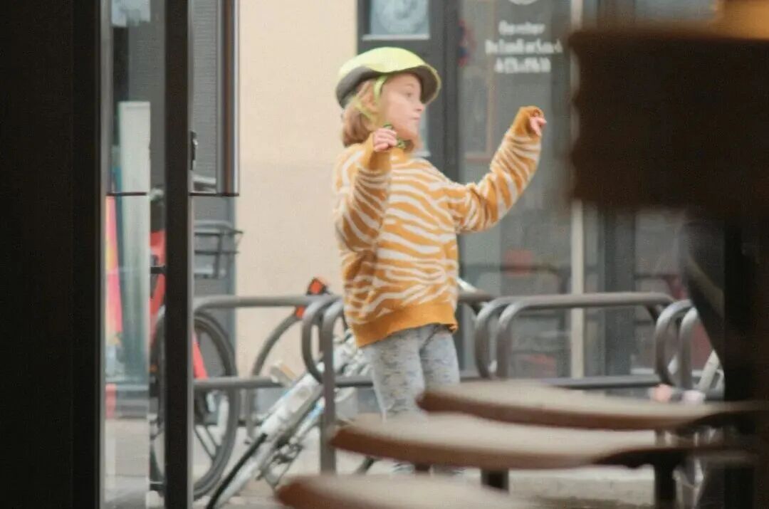 Child wearing helmet dances outside shop