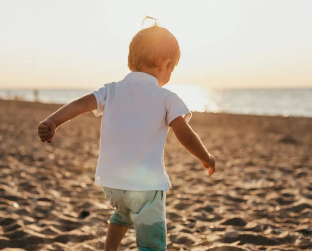 boy standing on sand near sea
