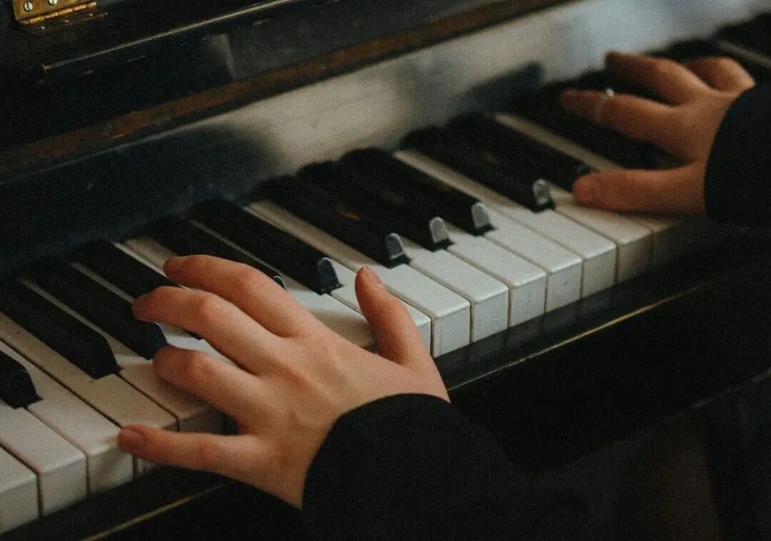 hands playing piano with a note