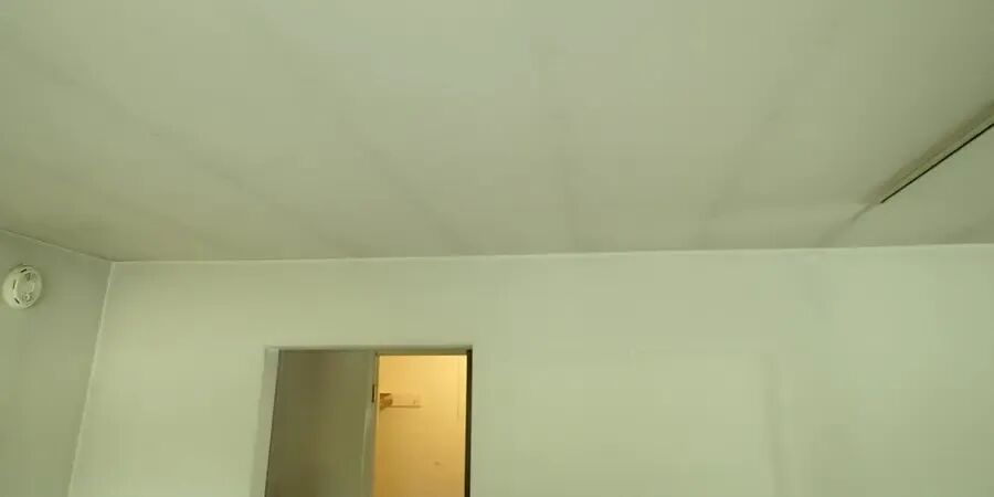 空房间的天花板上有平行灰带，右侧墙面也有竖向灰带