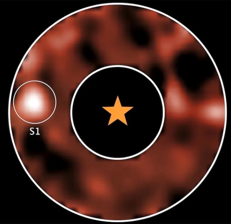 Concentric white circles with a star in the centre and a red and black hazy background. The image from Webb’s MIRI (Mid-Infrared Instrument), which uses a coronagraphic mask to block the bright glare from Alpha Centauri A, reveals a potential planet orbiting the star.