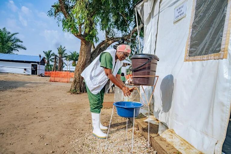 A health worker washes her hands at an outdoor wash station in an Ebola treatment center in the Democratic Republic of the Congo.
