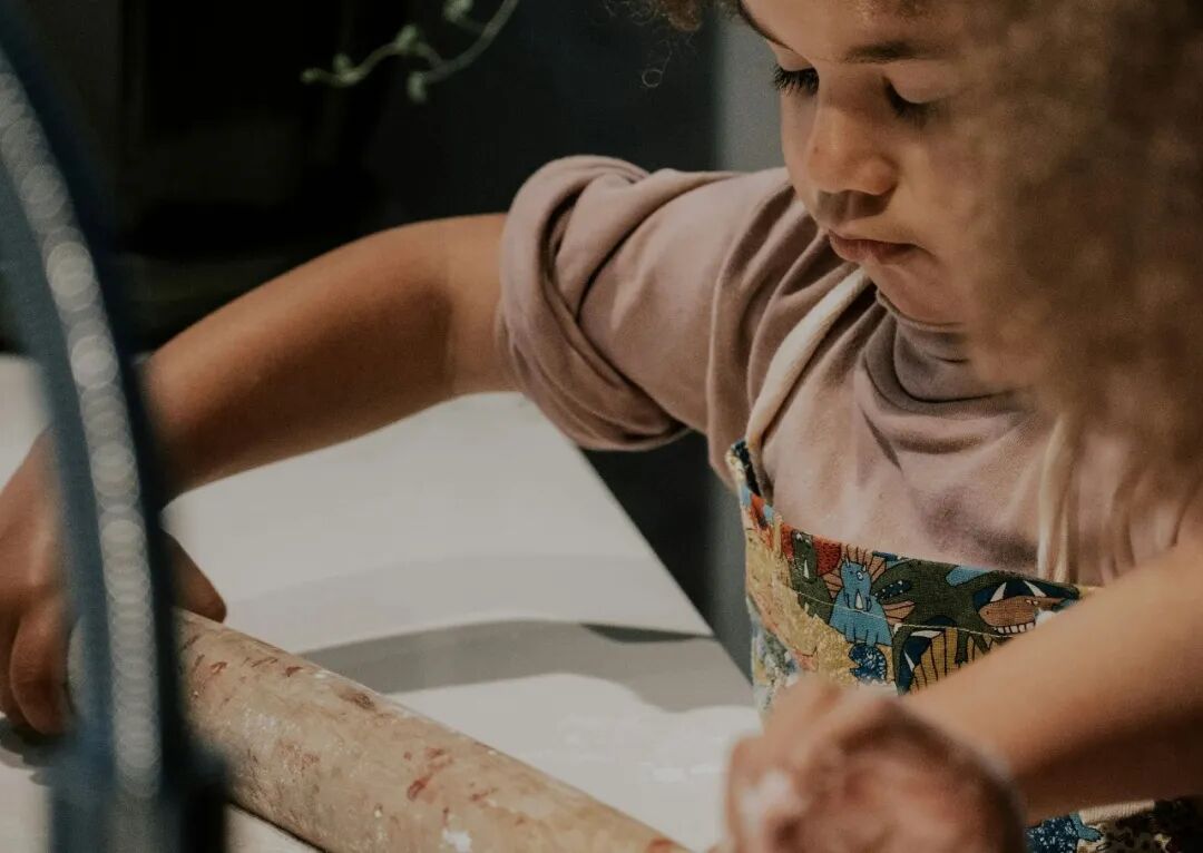 a little girl is making a doughnut on a counter