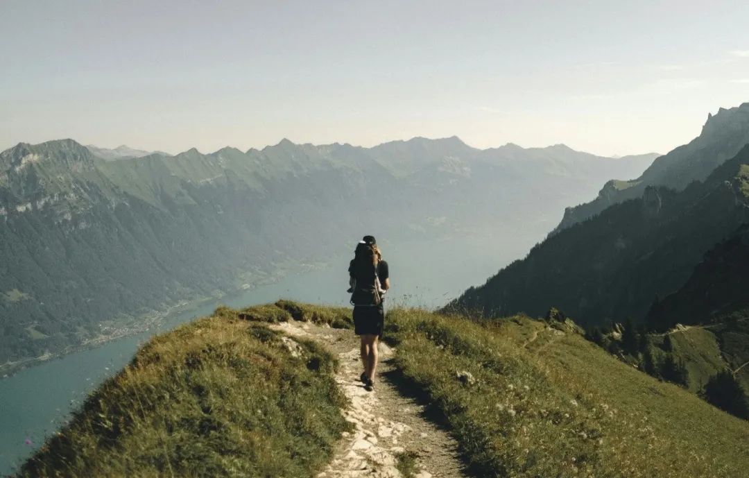 person hiking above mountain overlooking river